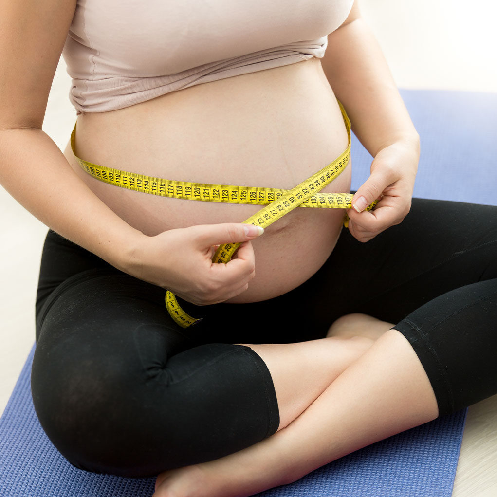 closeup-photo-pregnant-woman-measuring-belly-with-tape