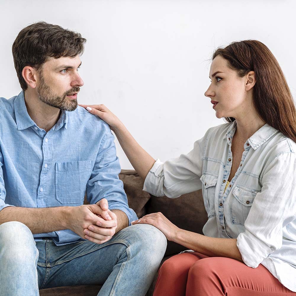 el-joven-marido-sentado-en-el-sofa-hablando-de-problemas-la-esposa-escuchando-cuidadosamente